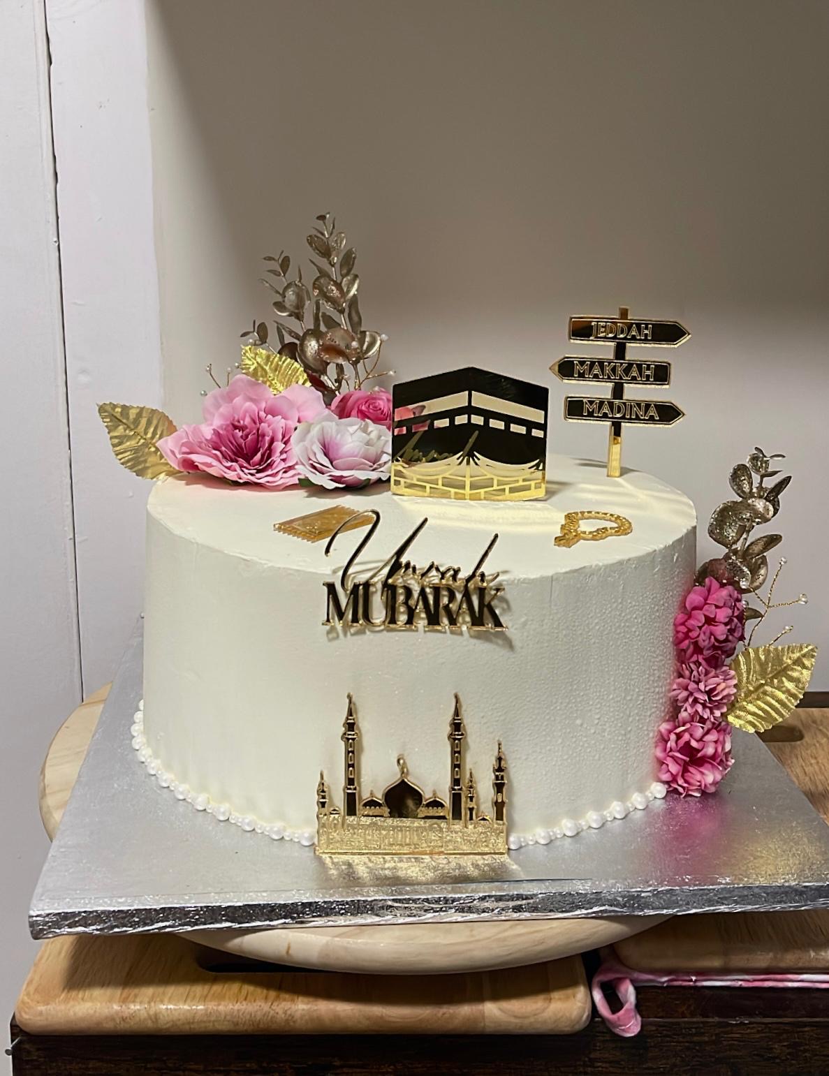 White Umrah Mubarak cake with gold detailing and flowers