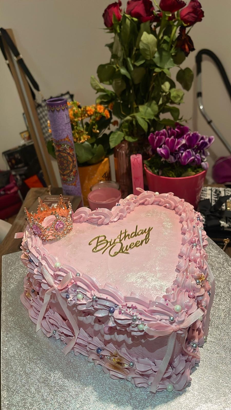 Pink heart-shaped birthday cake with piped ribbons